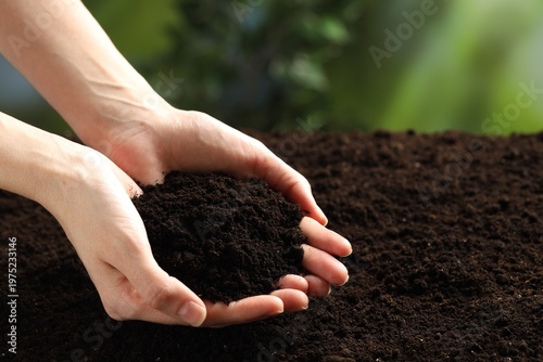 Woman with fresh soil on blurred background, closeup