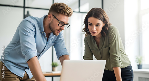 Two colleagues working together on a laptop in an office environment