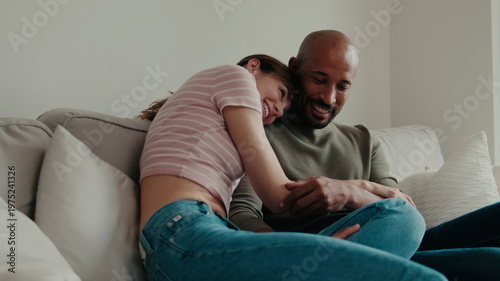 Couple Cuddle On Sofa At Home