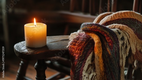 A lit candle on a wooden chair with a cozy, colorful blanket draped over it