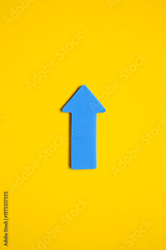 Blue Arrow Pointing Upwards on Bright Yellow Background for Success Concept