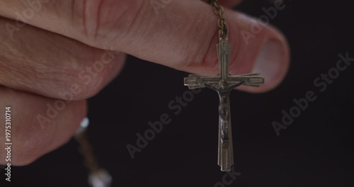 Extreme Close-up of fingers using rosary beads to pray
