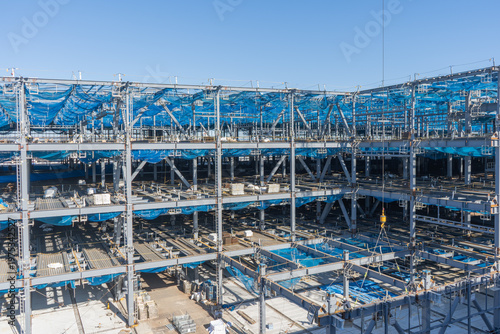 Obraz na płótnie 大規模鉄骨建築工事の全景と仮設足場・梁本締め作業の現場