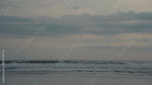 People riding a red scooter on the beach at sunset