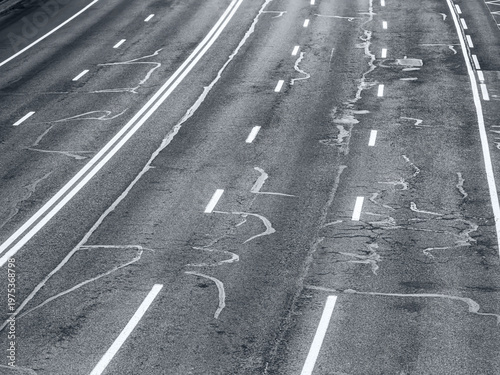 empty city street with white road markings on weathered cracked asphalt. perspective view.