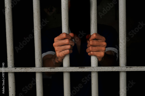 Εκτύπωση καμβά Close up of a prisoner hand gripping rusty iron bars behind a jail cell or detention center