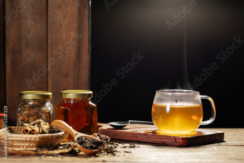 A cup of hot tea with ingredients on a wooden table