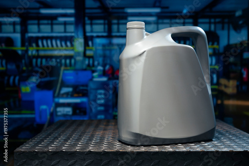 A gray gallon or bottle of engine oil sits on a metal table in a professional automotive service center.