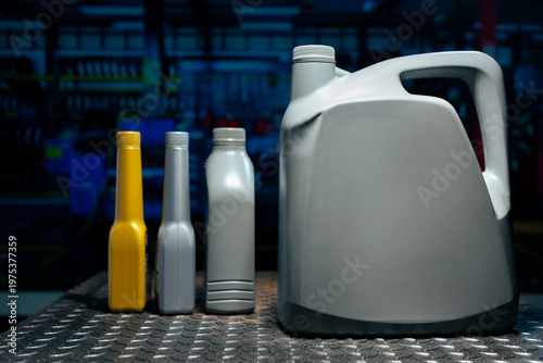 Generic plastic engine oil and chemical additive bottles on metal workbench in car repair shop.