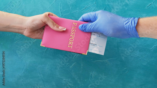 Flight check-in. Quarantine travel. Customs officer hand in protective glove giving pink passport ticket to female passenger on blue.