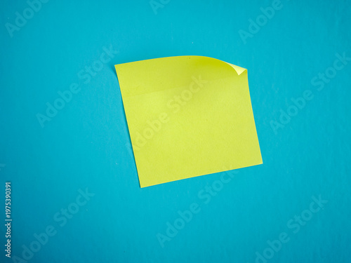Yellow Sticky Note with Curled Corner on Blue Textured Background - Top View with Copy Space