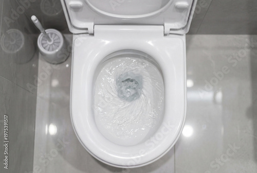 Top down view of a white ceramic toilet bowl flushing with swirling clean water