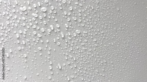 Against a light gray background, large droplets of water flow down in streams. The concept of rain, moisture, drops, moisture. High quality 4k footage 