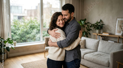 Warm emotional scene of a happy couple hugging in a cozy modern living room filled with natural light. Lifestyle concept representing love, connection, and togetherness. Ideal for relationship, family