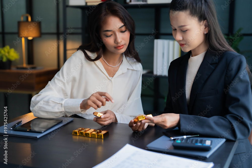 Fototapeta premium Two Asian businesswoman trading gold bar together