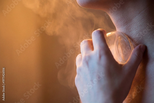 Woman's hand applying a glass cupping therapy cup to her neck