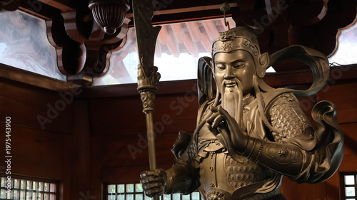 Foto A statue of a figure in armor, standing tall within an interior space that seems to be part of a traditional Asian structure