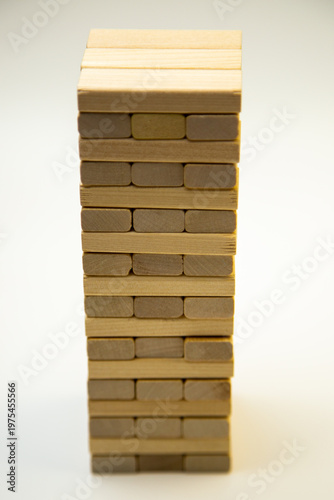 Close-up of a tower made of wooden bars, a game of gengo, standing on a white background. The concept of board games, business, construction. High quality photo