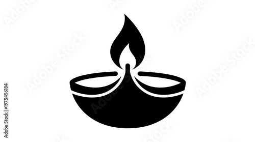 A lit diya lamp burns brightly on a decorative plate indoors.