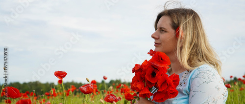 Woman poppies field. Happy woman is resting in the rays of the sun sitting in the poppy field.