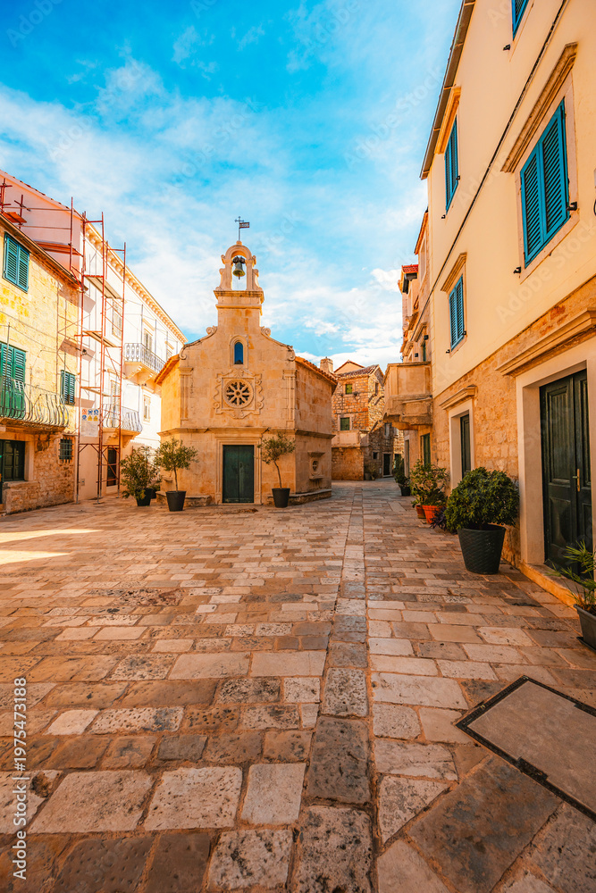 Fototapeta premium Jelsa town on Hvar island, with traditional Dalmatian stone architecture and boats moored in the harbor, Croatia.