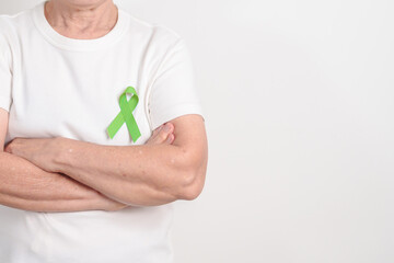 Elderly with light Green Ribbon for concept of May Celiac Awareness month, Lyme disease, September Lymphoma, Mental Health Awareness month and October Liver cancer. Health and world cancer day