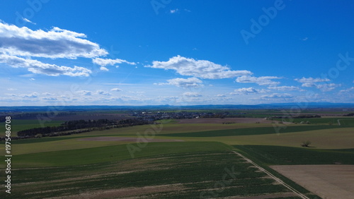 Beautiful landscape with a lush green field under a clear blue sky. The image captures a peaceful countryside scene with fresh colors, open space, and a natural, calming atmosphere.