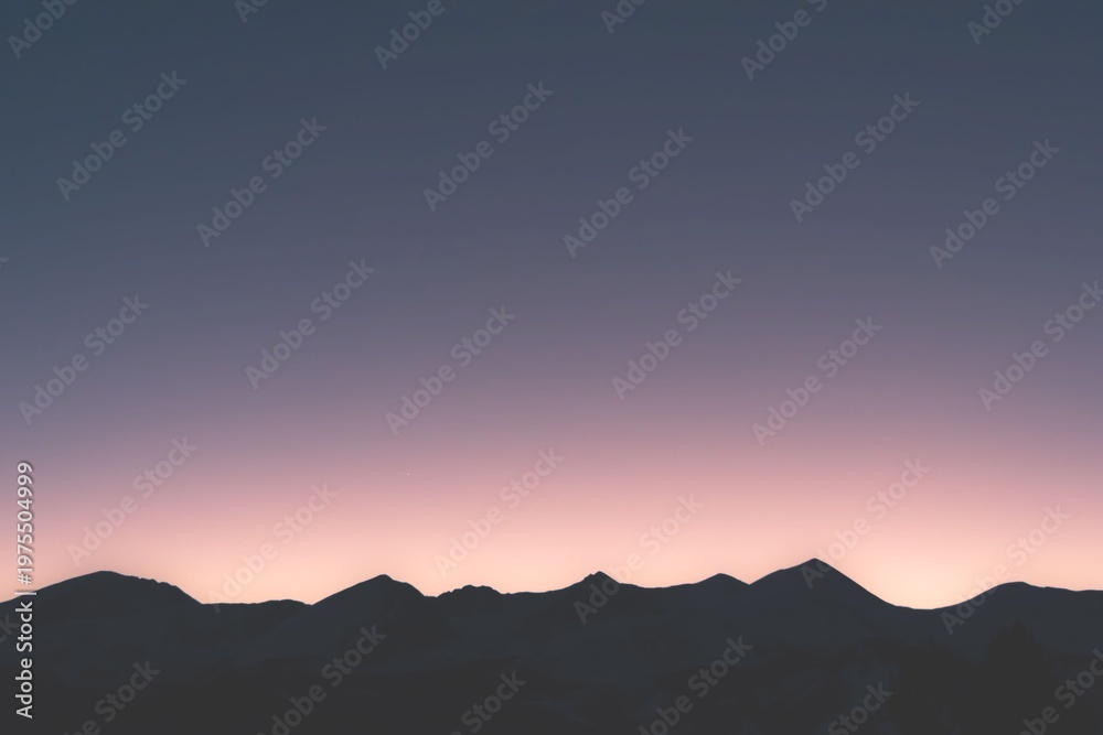 Obraz premium A serene mountain landscape at sunset with a vibrant sky
