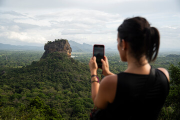 Tourist taking photo of Lion Rock Sigiriya landscape with mobile phone