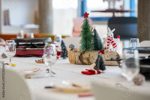 Table avec appareil à raclette décoré pour les fêtes de fin d'année. Un plat traditionnel suisse appelé raclette, composé de fromage fondu, de pommes de terre cuites et de viande grillée.