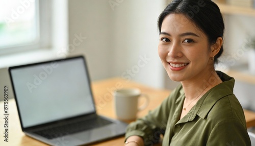 Young woman smiling at laptop while working remotely in cozy office setting