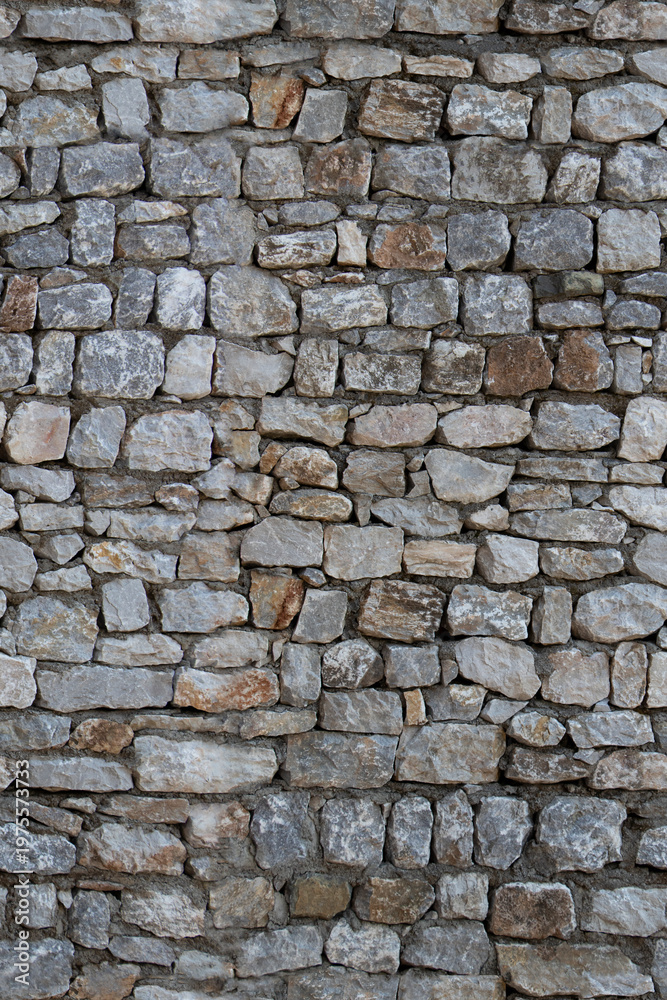 Fototapeta premium Old stone wall with irregular rough texture and weathered appearance