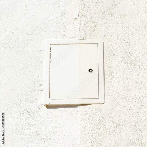 White square utility access hatch on textured wall