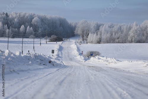 winter rural road with traffic signs power lines and snow covered landscape