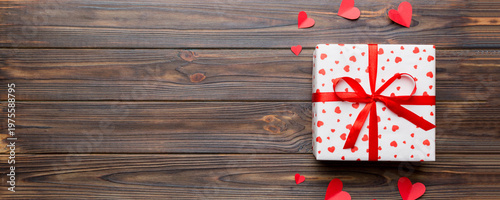 Valentine day composition: red gift box with bow and heart. Christmas present. View from above. Space for text. Holday greeting card