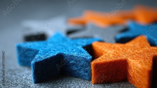 Close up of sparkly blue and orange star shapes scattered on a textured gray surface with shallow depth of field creating a dreamy bokeh effect