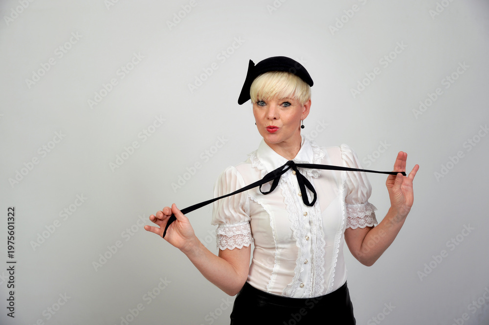 Naklejka premium Freche Best-Ager Frau im modernen Retro-Outfit mit Hut und verspielter Pose, selbstbewusstes Fashion- und Lifestyle-Porträt mit Copyspace