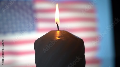 The candle flame glows against the blurred background of the US flag. Mourning in the United States of America for the dead. High quality FullHD footage