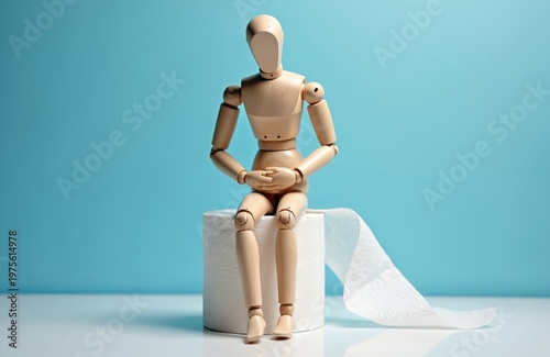 Wooden mannequin figure sits on toilet paper roll with stomach pain. Concept for constipation or digestive issues. Mannequin on wc paper relates to health problems and discomfort.