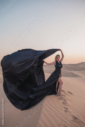 Close up portrait of elegant blond woman in black dress in desert, UAE. 