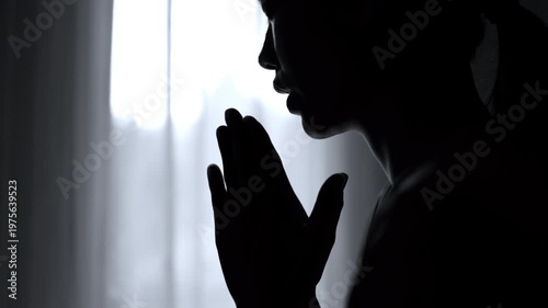 Silhouette of a woman  Praying hands with faith in religion and belief in God. Power of hope or love and devotion. 4K slow-motion video.
