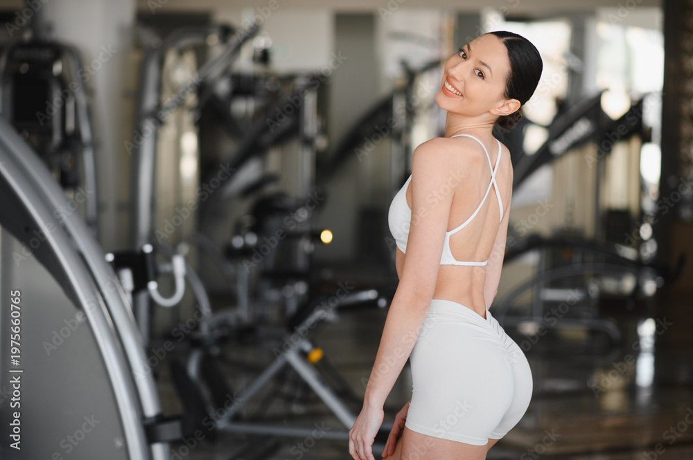 Fototapeta premium Young woman smiling, standing in a gym