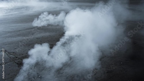 Thick white smoke or dry ice fog rolling across a dark concrete ground, atmospheric background texture.