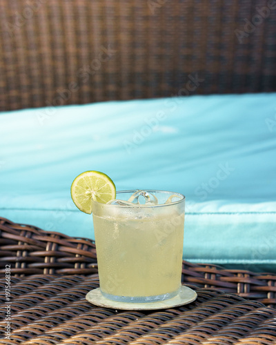 Tableau sur toile Chilled Lime Margarita with Fresh Lime Slice on Wicker Table by Pool