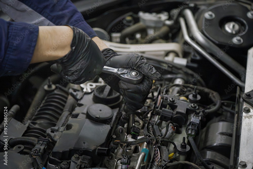 Obraz premium Mechanic in black gloves repairs engine with ratchet