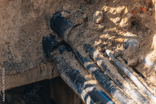 Φωτογραφία Underground utility pipes and cable conduits partially buried in a trench