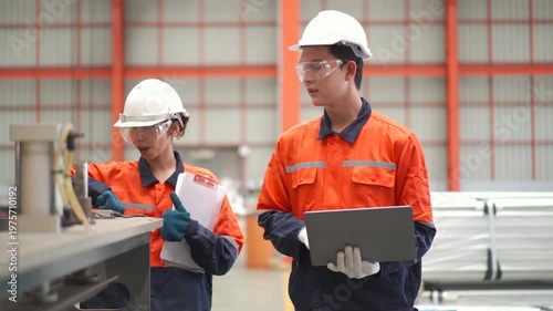 Two engineers in safety gear using tablet inspecting in modern factory