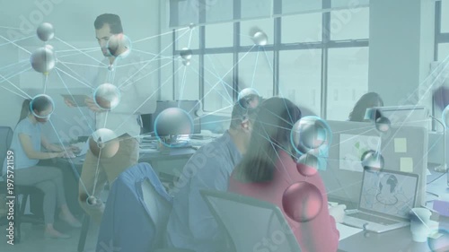 Standing man tapping tablet causing molecular overlay while team leaning at laptop for tech review