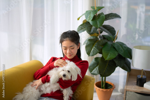 The Asian pretty woman is spending leisure time with her dog at the living room.