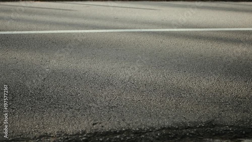 Close view of asphalt road with white lane marking as vehicle passes along roadway